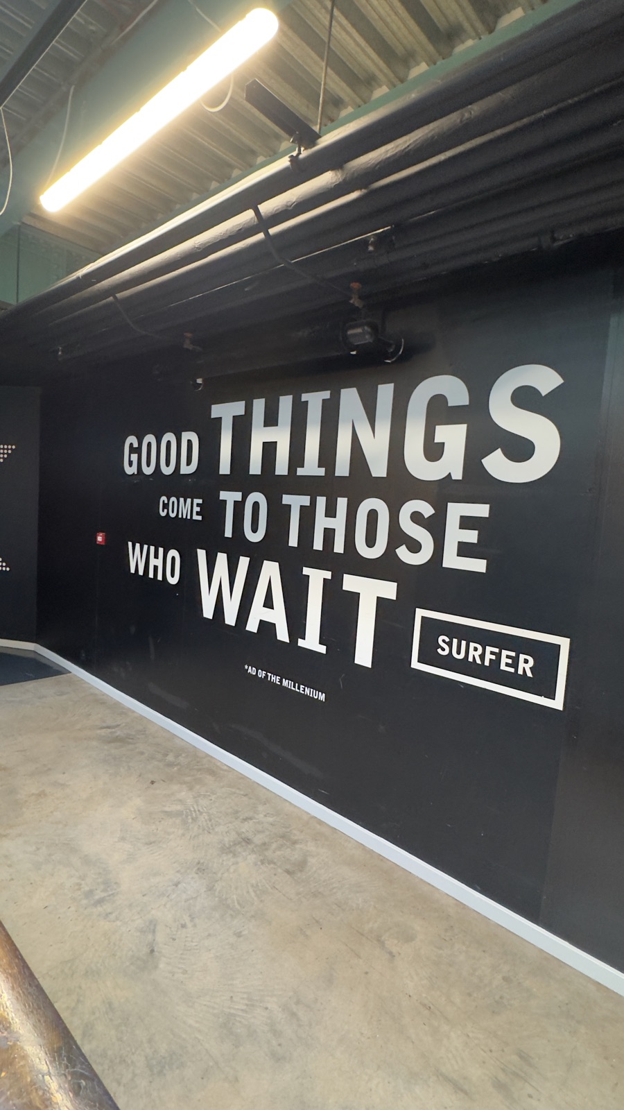 Σκούρος τοίχος με το σλόγκαν της Guinness Good Things Come To Those Who Wait σε μεγάλα λευκά γράμματα