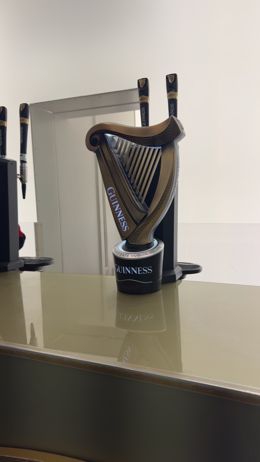 Βρύση Guinness σε σχήμα άρπας πάνω σε ορειχάλκινο πάγκο κάτω από δύο μαύρα στόμια μπίρας