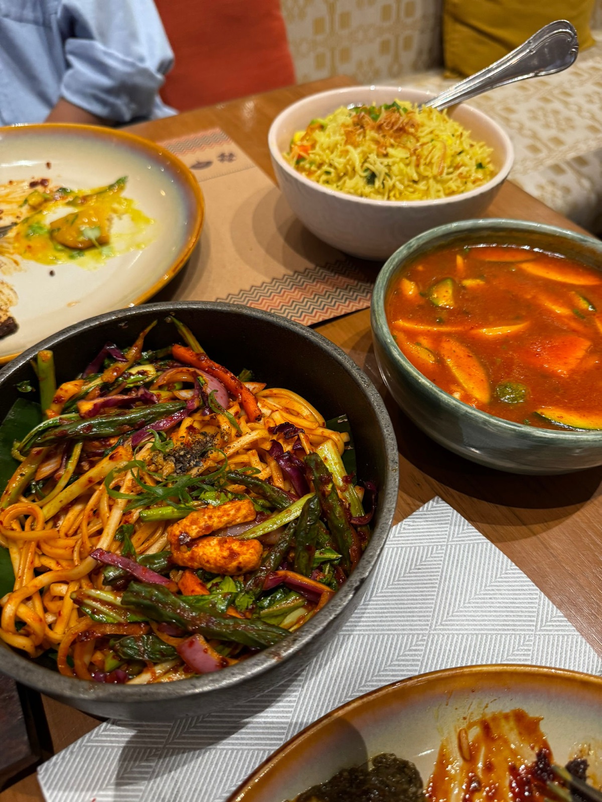Τηγάνι με πικάντικα σοταρισμένα noodles με τόφου, ένα μπολ τηγανητό ρύζι και μια κόκκινη σούπα κάρι σε τραπέζι εστιατορίου