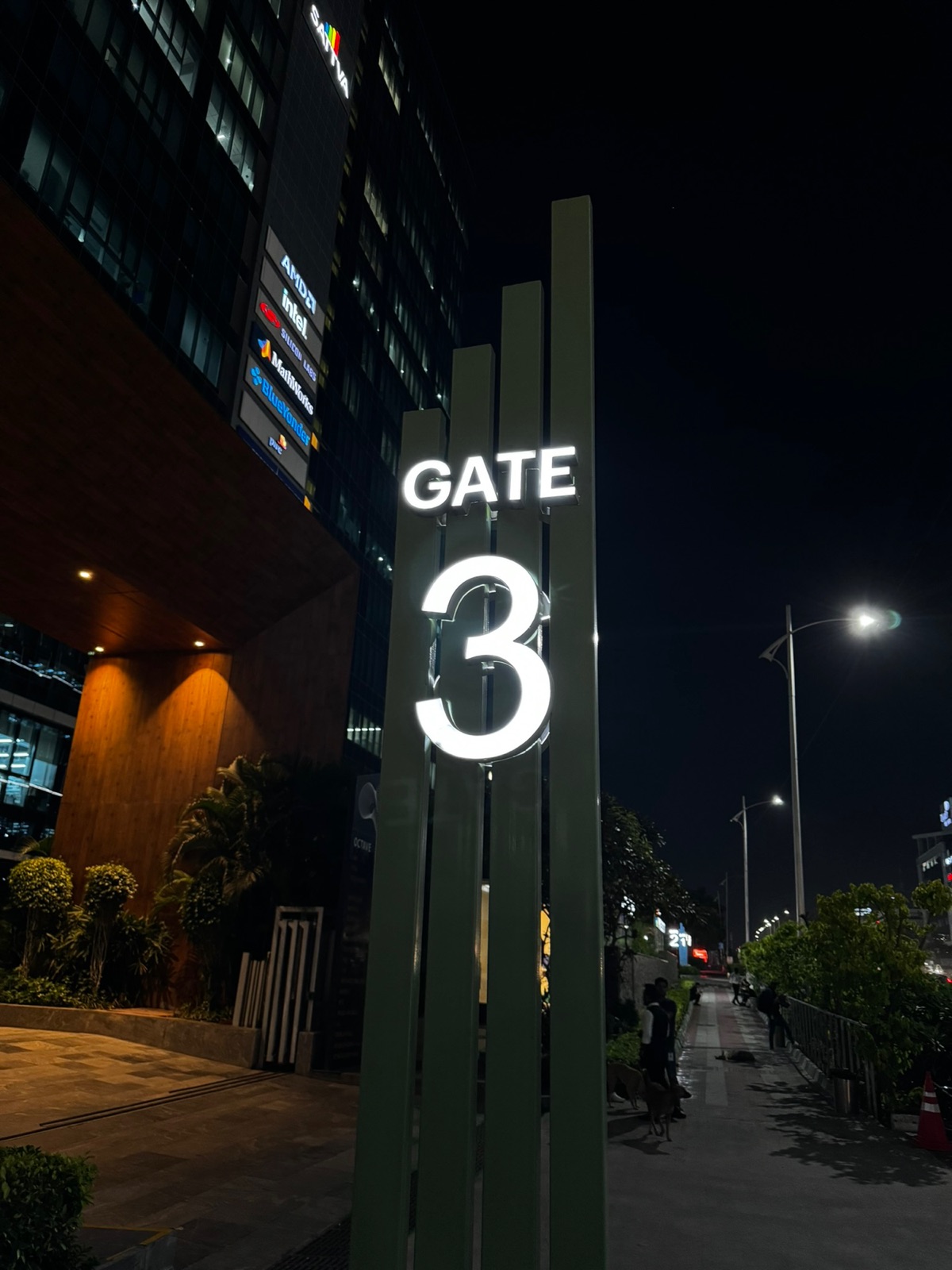 Φωτισμένος πυλώνας της Gate 3 τη νύχτα με μια πινακίδα ενοίκων που αναφέρει AMD, Intel, Silicon Labs, MathWorks και BlueYonder