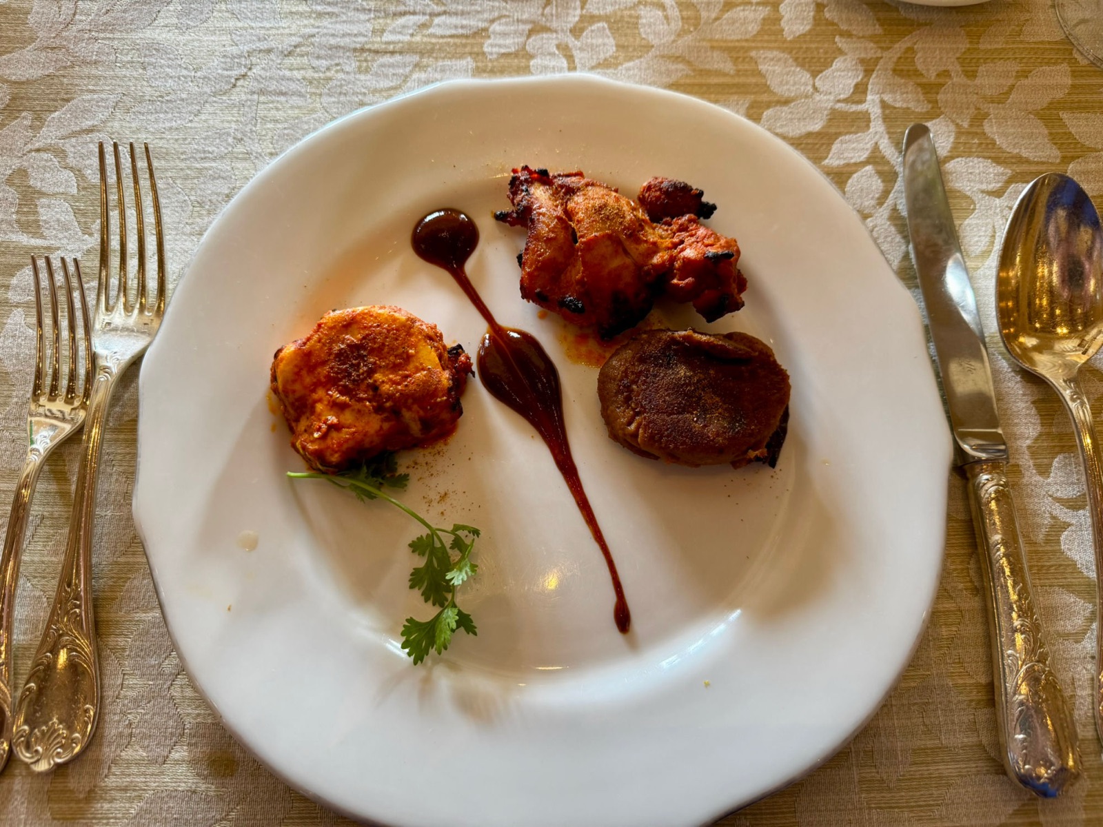 Λευκό πιάτο με τρία εδέσματα tandoori γαρνιρισμένα με κόλιαντρο και σταγόνες chutney ταμαρίνθου