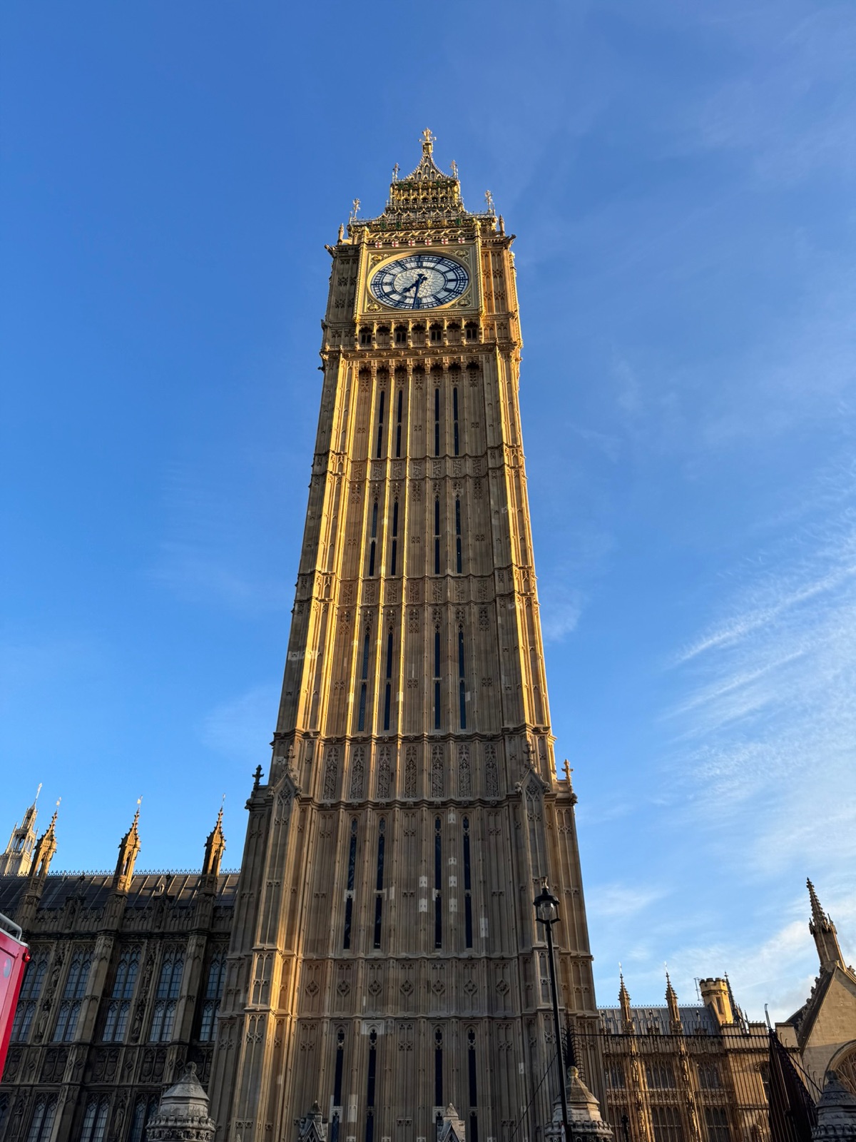 Ο πύργος του ρολογιού του Big Ben να γεμίζει το κάδρο κόντρα σε βαθύ γαλάζιο ουρανό, το επιχρυσωμένο καντράν να πιάνει το βραδινό φως