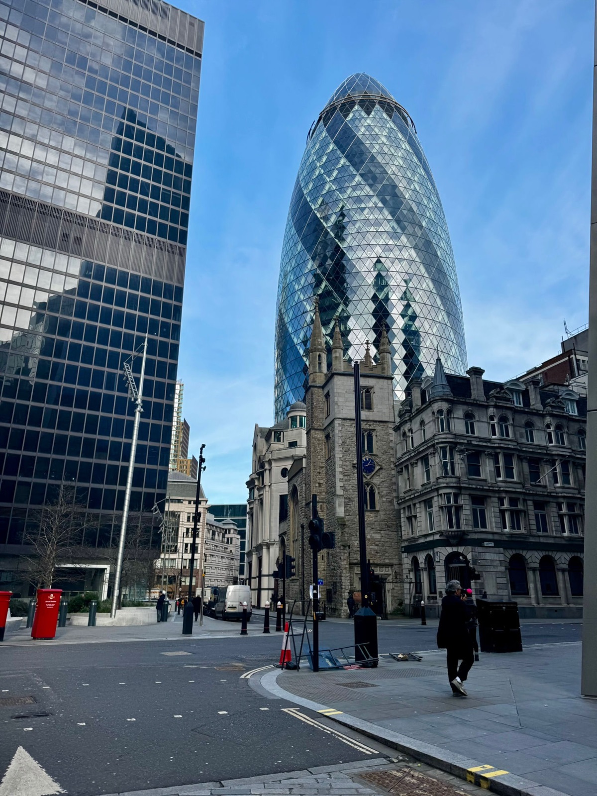 Το Gherkin κάτω από γαλάζιο ουρανό με τον πέτρινο πύργο της εκκλησίας St Andrew Undershaft ακριβώς μπροστά του