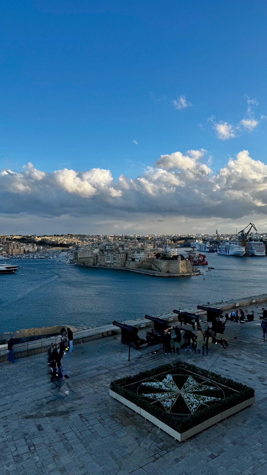 Μια πέτρινη βεράντα κάτω από τους κήπους με μια σειρά από μαύρα κανόνια στραμμένα πάνω από το Μεγάλο Λιμάνι, ένα παρτέρι σε σχήμα οκτάκτινου σταυρού στο πλακόστρωτο, η οχυρωμένη απέναντι ακτή και πλοία πιο πέρα