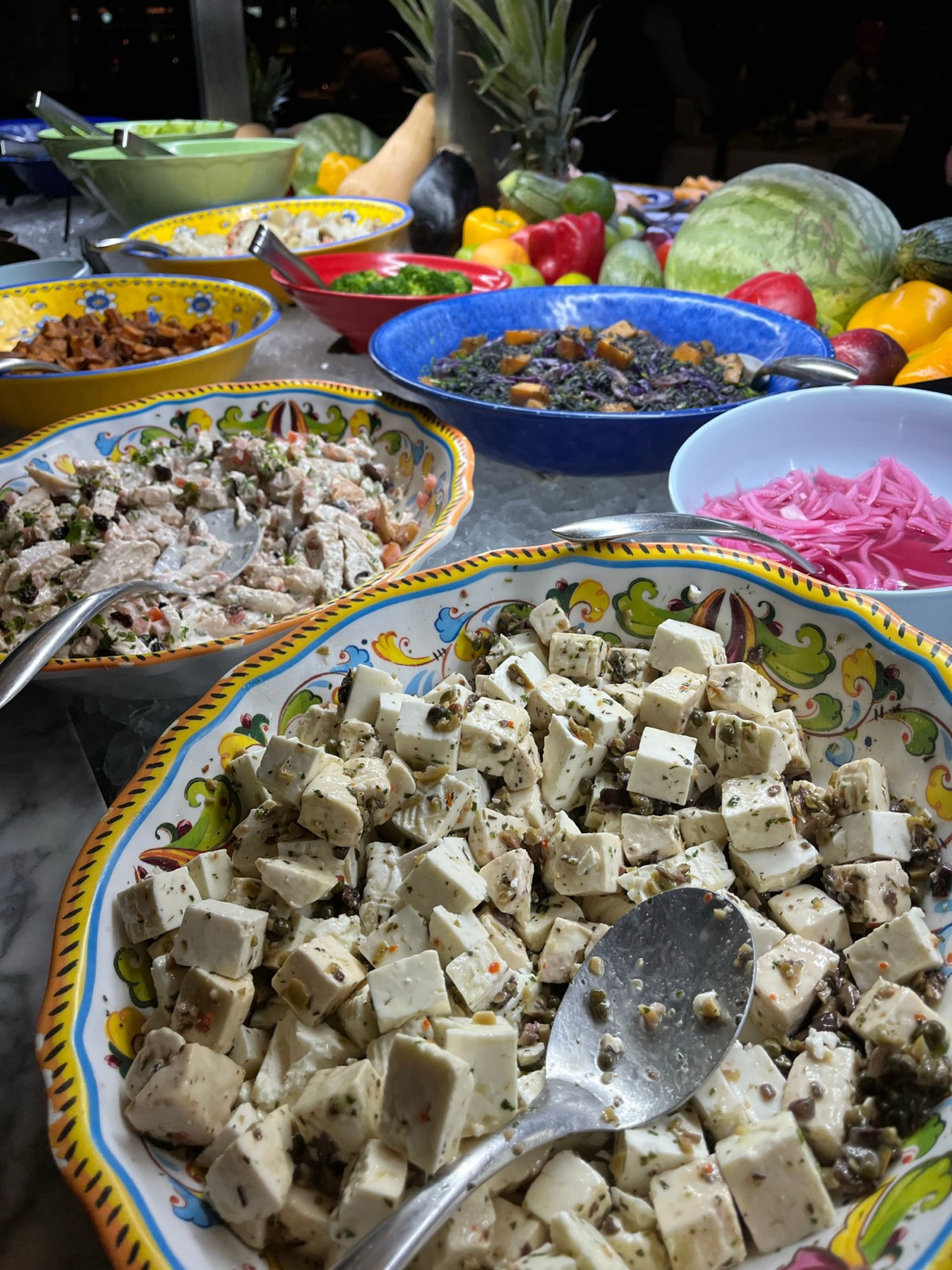 Το σαλατμπάρ της churrascaria με κύβους μαριναρισμένης panela, σαλάτα κοτόπουλο και κόκκινα τουρσί κρεμμύδια σε ζωγραφισμένα στο χέρι μπολ