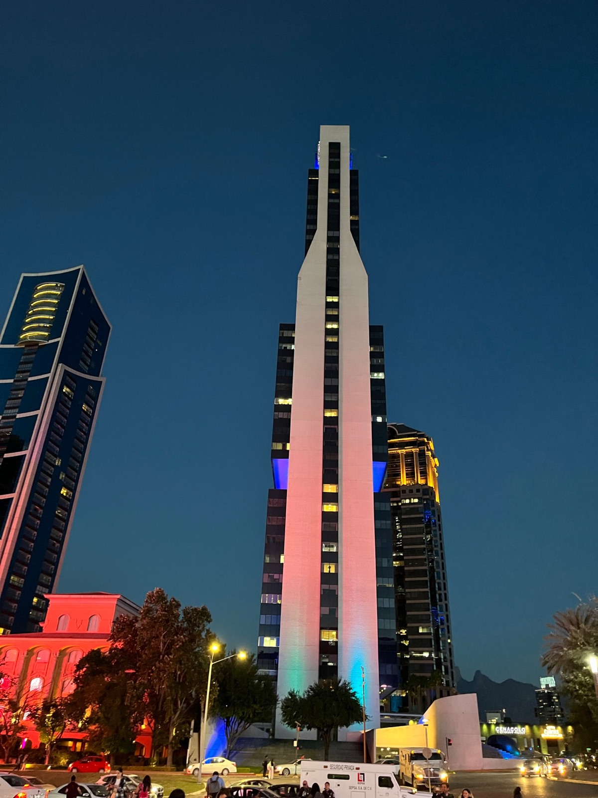 Ο λευκός μονολιθικός Torre Avalanz φωτισμένος σε ροζ και μπλε πάνω σε έναν βαθύ μπλε νυχτερινό ουρανό