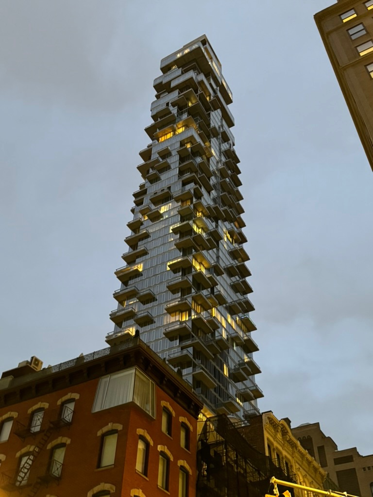 56 Leonard Street, the stacked cantilevered glass tower in Tribeca, rising at dusk above a red-brick nineteenth-century building
