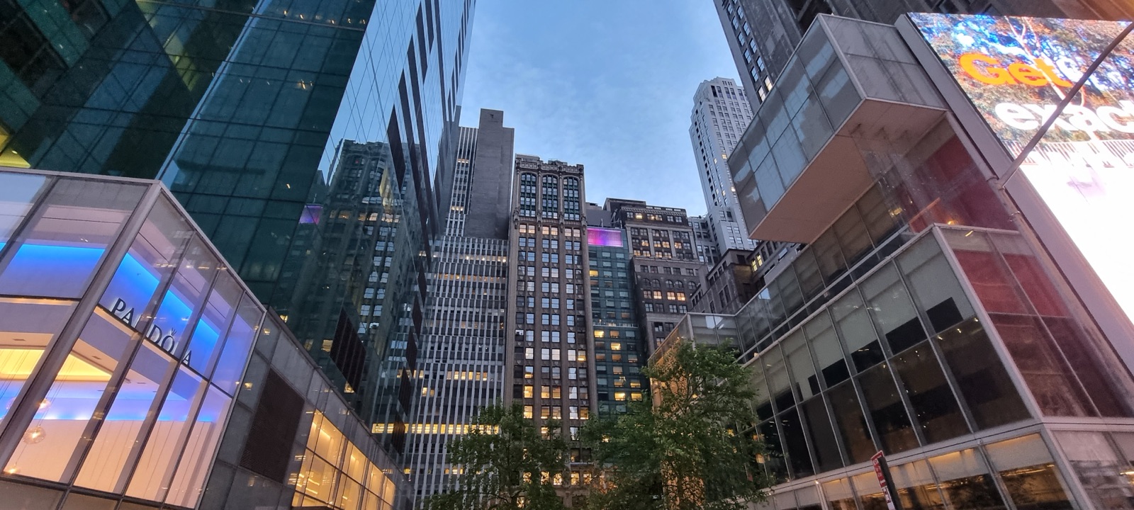 Glass office buildings photographed looking straight up at dusk, their facades reflecting the last violet light