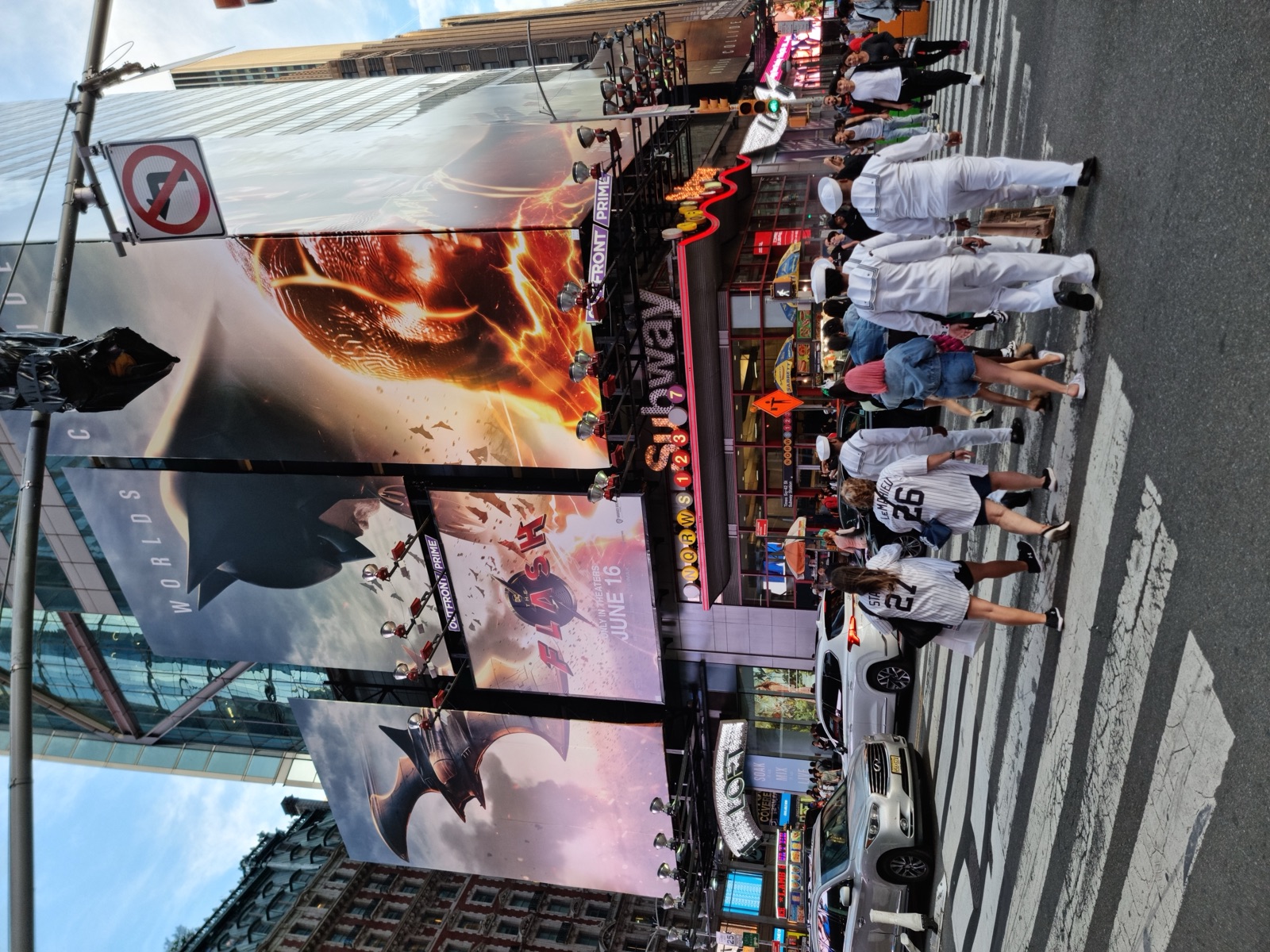 Sailors in white dress uniforms crossing a Times Square street on the pedestrian crossing among other pedestrians