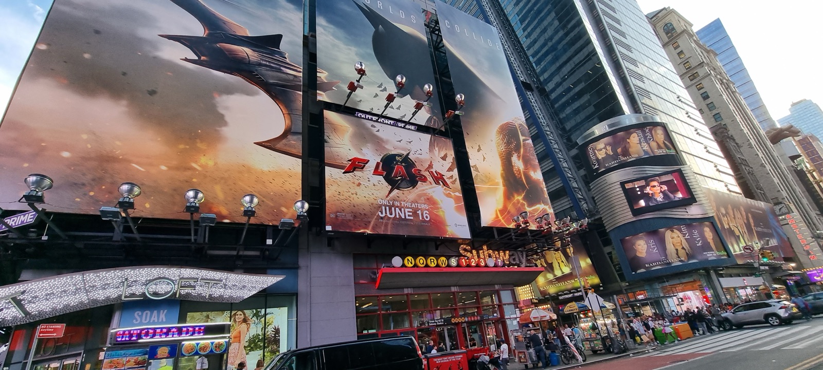 Times Square in daylight with huge film billboards on the buildings and traffic and pedestrians below
