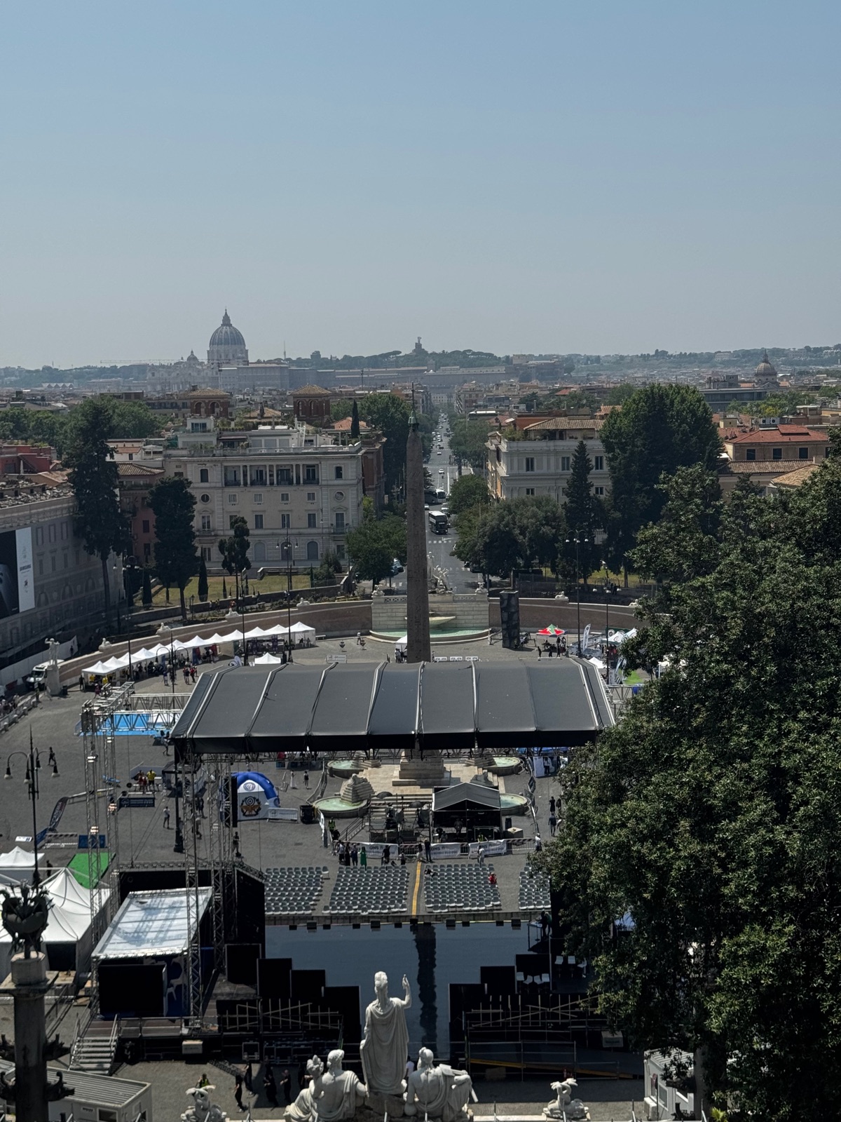 Η θέα από τη βεράντα του Pincio πάνω από την Piazza del Popolo με τον οβελίσκο της και μια προσωρινή σκηνή εκδήλωσης, η πόλη να απλώνεται επίπεδη μέχρι τον θόλο του Αγίου Πέτρου στον ορίζοντα