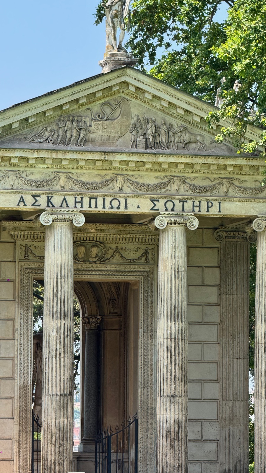 Η στοά του ναού από κοντά, ιωνικοί κίονες και ένα σκαλισμένο αέτωμα με μια ελληνική επιγραφή προς τον Ασκληπιό από πάνω